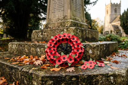 Wreath of red remembrance poppies on the steps of a village war memorial, illustrating Remembrance Sunday